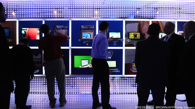 Peole gather around a display of laptops