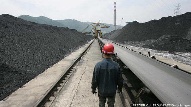 A miner walks between mounds of coal wai