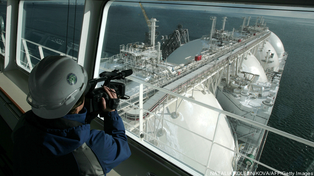 A cameraman films an LNG tanker docked a
