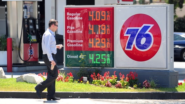 A man walks past gas prices posted on a