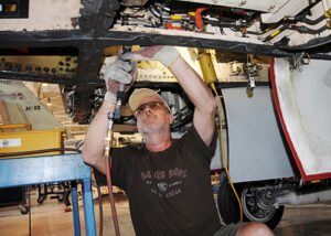 Kai Boyce makes a repair in the APU compartment on the aft right side of an F/A-18 hornet at Cecil Commerce Center.