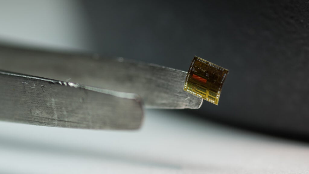 A flexible microchip, lightly held by tweezers.