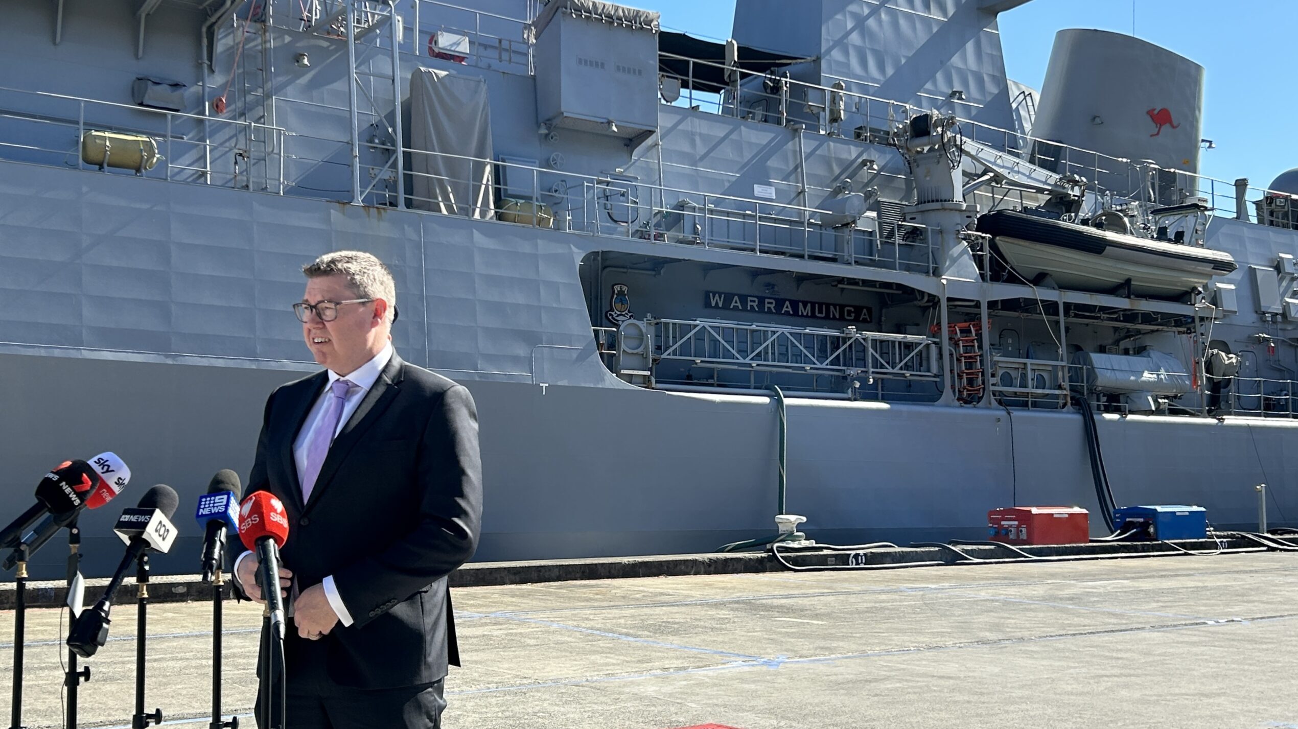 Pat Conroy, Australian defense industry minister, takes press questions about long-range missile purchases in front of HMAS Warramunga, berthed in Sydney